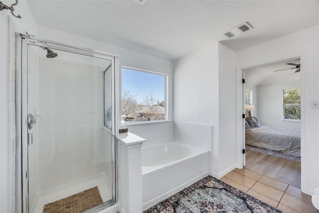 ensuite bathroom featuring tile patterned floors, visible vents, a garden tub, a stall shower, and connected bathroom