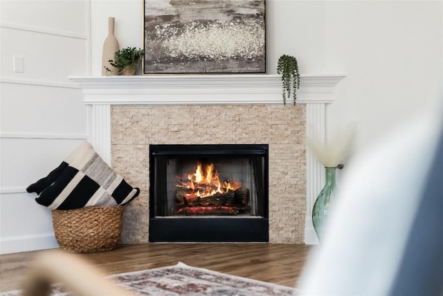 interior details featuring wood finished floors and a warm lit fireplace