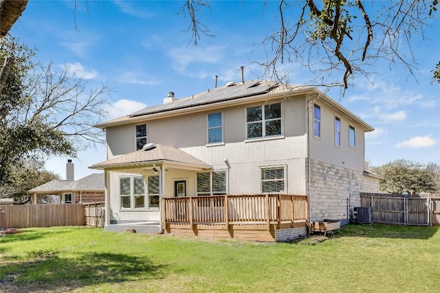 back of property featuring central AC, roof mounted solar panels, a fenced backyard, a deck, and a yard