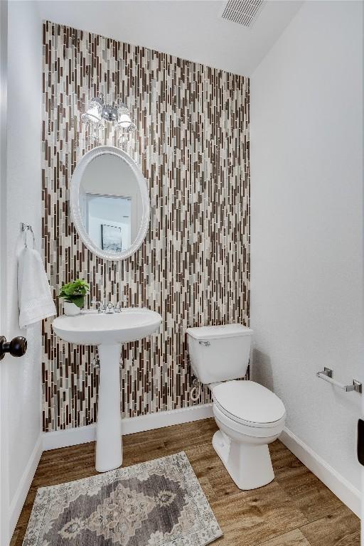 bathroom with visible vents, baseboards, toilet, and wood finished floors