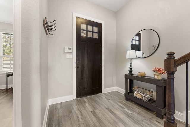 entryway featuring baseboards, wood finished floors, and stairs