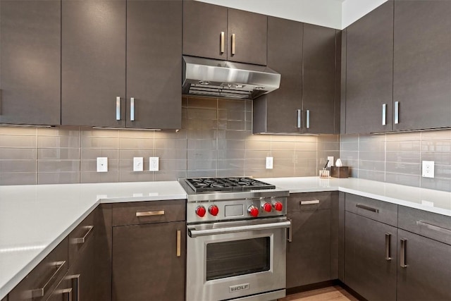 kitchen with under cabinet range hood, backsplash, dark brown cabinetry, and designer range