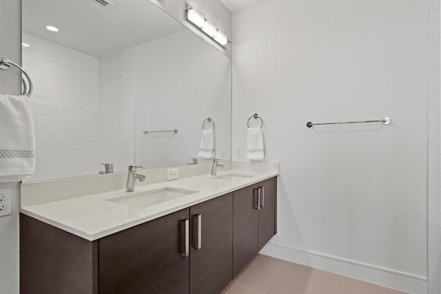 bathroom featuring a sink, baseboards, double vanity, and tile patterned floors