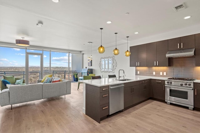 kitchen with a sink, decorative backsplash, stainless steel appliances, under cabinet range hood, and open floor plan