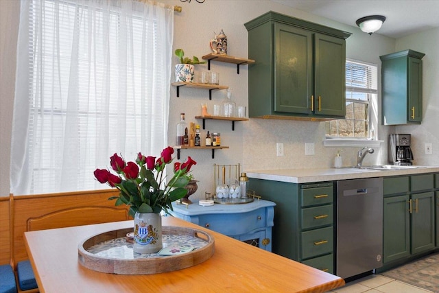 kitchen featuring a sink, open shelves, stainless steel dishwasher, and green cabinets