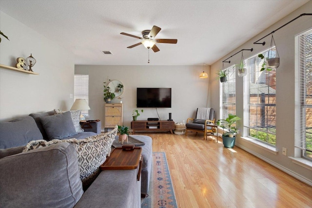 living room with visible vents, baseboards, light wood-type flooring, and ceiling fan