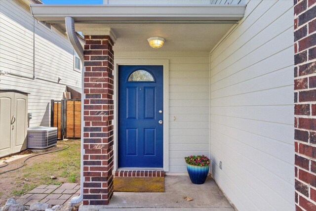 doorway to property featuring cooling unit and brick siding