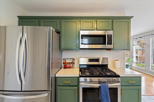 kitchen with appliances with stainless steel finishes, green cabinets, and light countertops