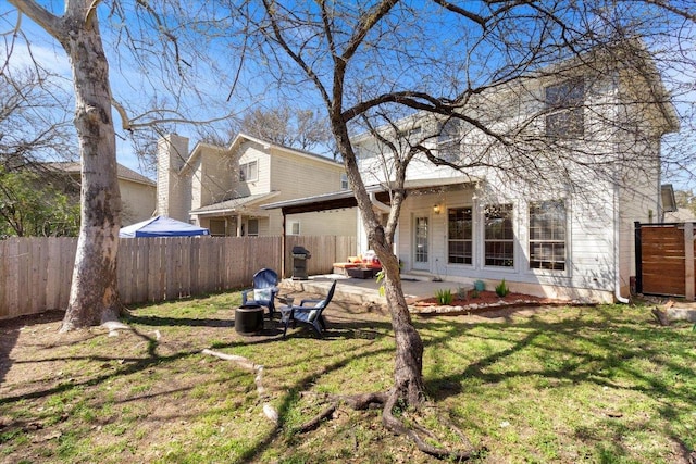 rear view of house featuring a patio, a yard, and a fenced backyard