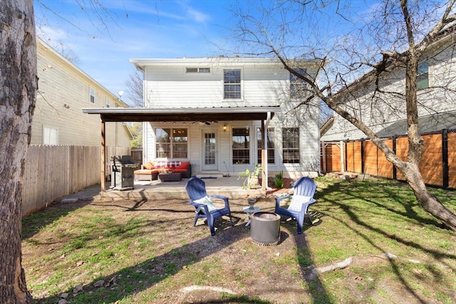 rear view of house with a patio area, a lawn, an outdoor living space with a fire pit, and a fenced backyard