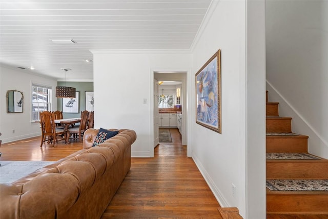 living room with stairway, baseboards, wood finished floors, and crown molding