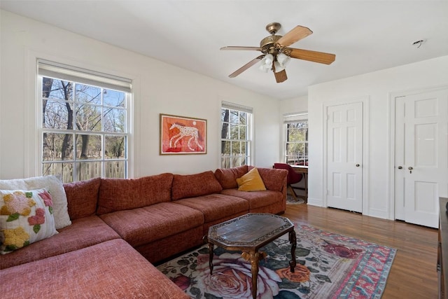 living area featuring ceiling fan, baseboards, and wood finished floors