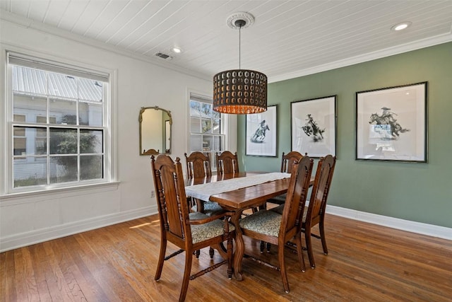 dining room featuring visible vents, baseboards, ornamental molding, and hardwood / wood-style flooring