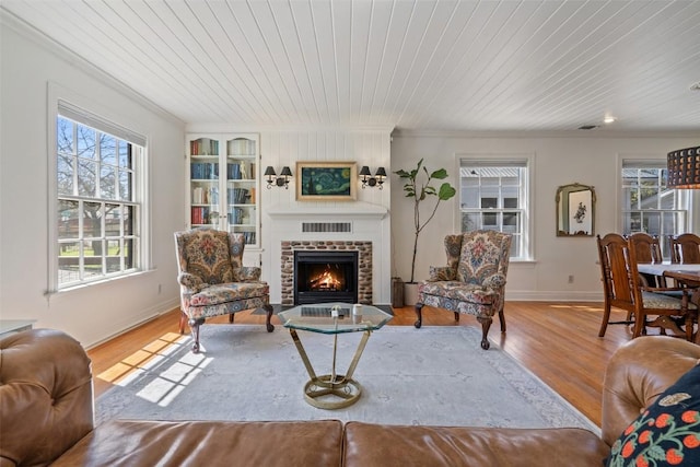 living area with a brick fireplace, wood ceiling, built in shelves, and wood finished floors