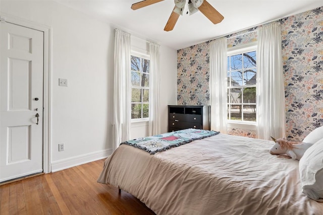 bedroom featuring wallpapered walls, wood finished floors, baseboards, and ceiling fan