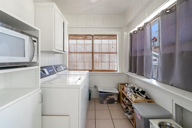 laundry room with washing machine and dryer, light tile patterned floors, and cabinet space