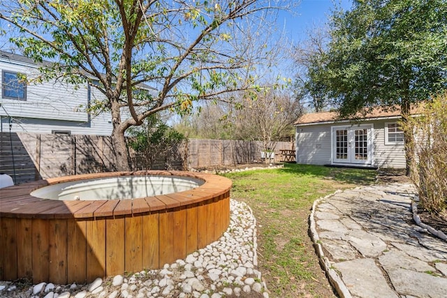 view of yard with french doors, a hot tub, and a fenced backyard