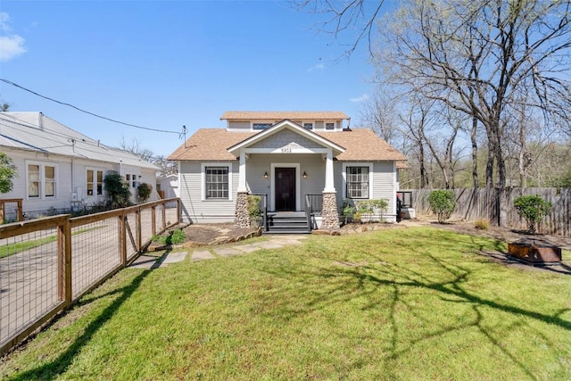 view of front of house featuring a front lawn, a fenced backyard, and roof with shingles