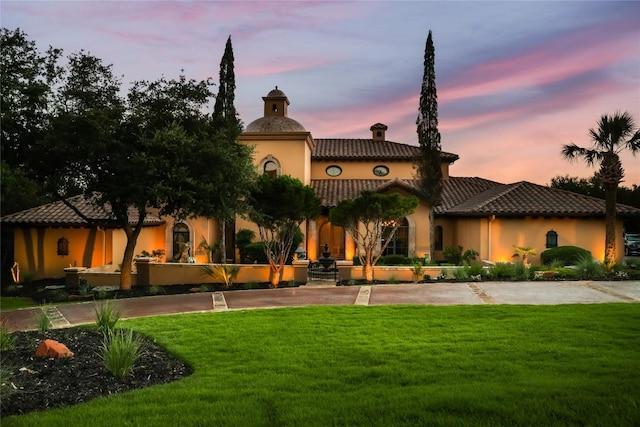 view of front of property featuring a front yard, a tiled roof, driveway, and stucco siding