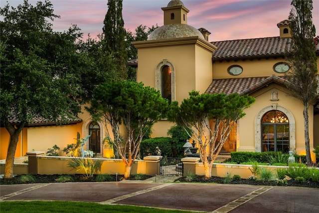 view of front facade with a fenced front yard, stucco siding, and a tile roof