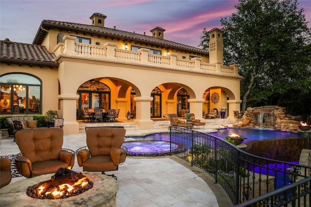 rear view of house with stucco siding, fence, an outdoor fire pit, a balcony, and a patio area