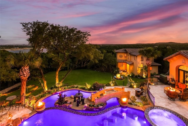 view of swimming pool with a patio, an outdoor fire pit, area for grilling, a pool with connected hot tub, and a lawn