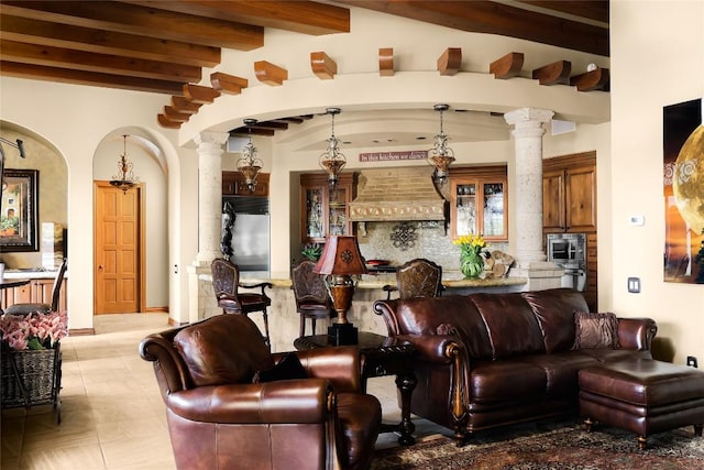 living area with decorative columns, beam ceiling, and arched walkways