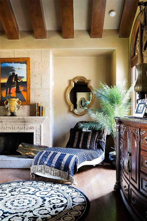 sitting room with wood finished floors, beamed ceiling, and a fireplace