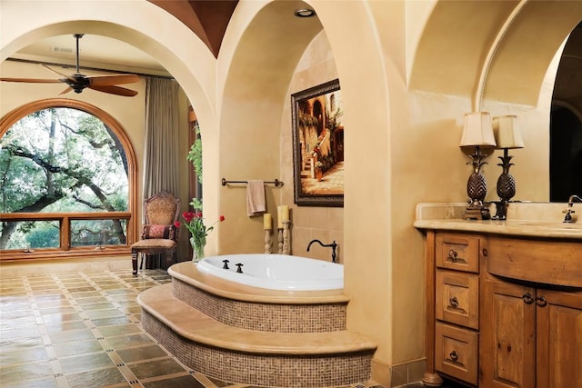 full bathroom with ceiling fan, a bath, and vanity