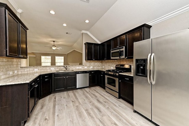 kitchen with vaulted ceiling, light wood-type flooring, appliances with stainless steel finishes, and ornamental molding