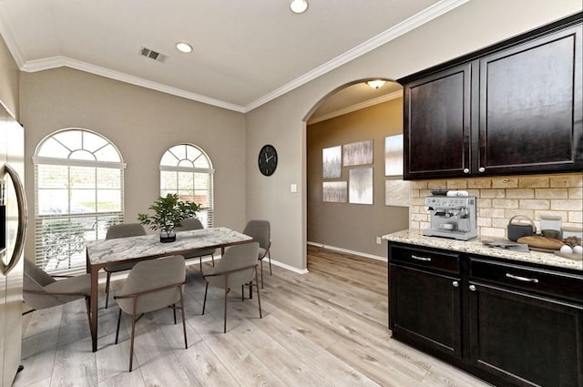 dining area with visible vents, crown molding, baseboards, light wood-style floors, and arched walkways