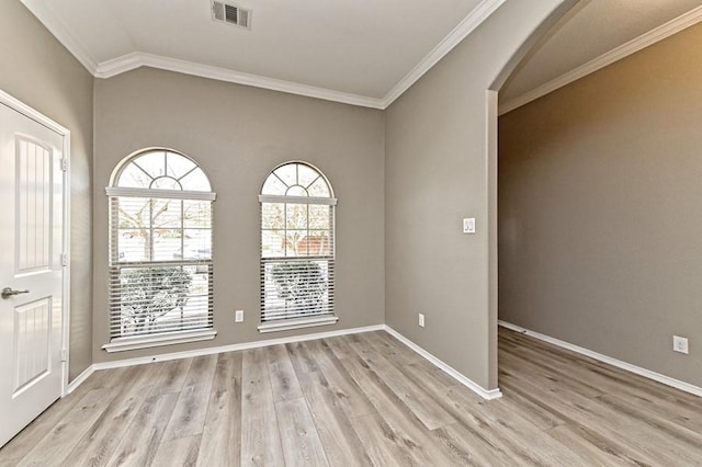 empty room featuring light wood-type flooring, visible vents, arched walkways, and baseboards