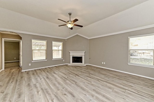 unfurnished living room with light wood finished floors, a fireplace with raised hearth, arched walkways, ceiling fan, and vaulted ceiling