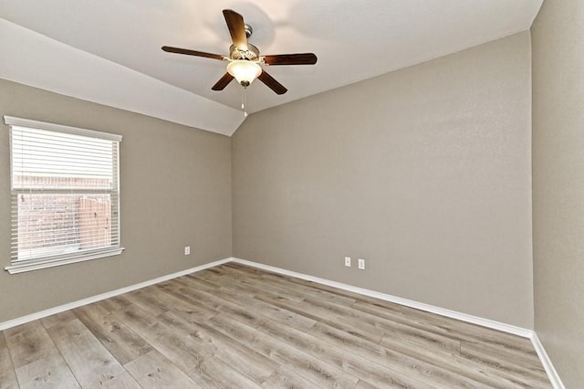 empty room featuring lofted ceiling, a ceiling fan, baseboards, and light wood finished floors