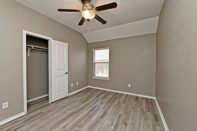 unfurnished bedroom with baseboards, wood finished floors, and vaulted ceiling