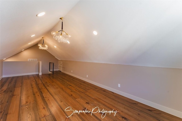 additional living space featuring vaulted ceiling, visible vents, baseboards, and hardwood / wood-style floors