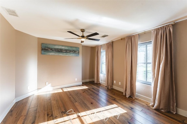 empty room with hardwood / wood-style flooring, baseboards, visible vents, and ceiling fan