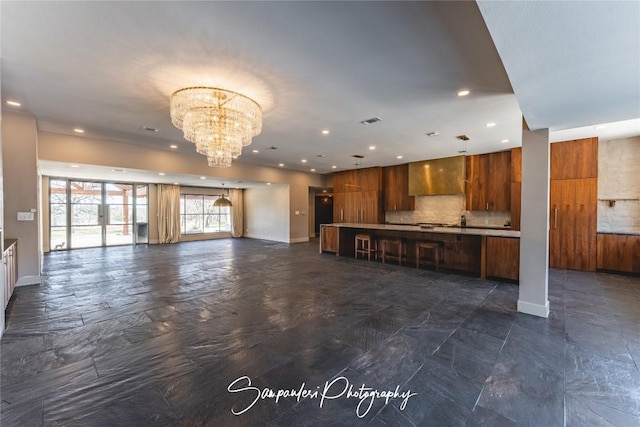 unfurnished living room featuring recessed lighting, baseboards, and a notable chandelier