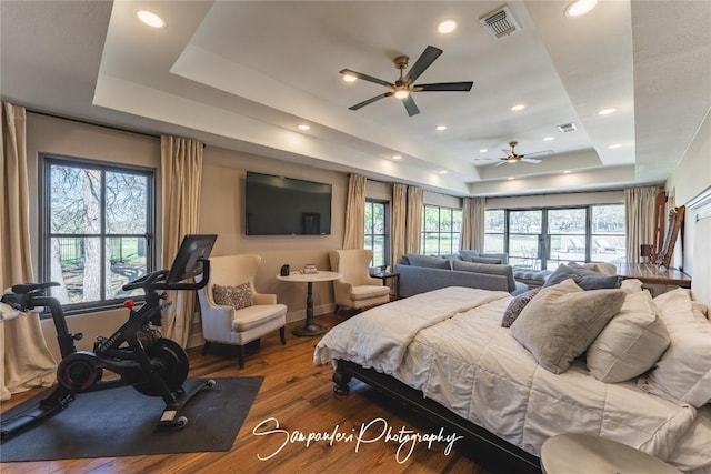 bedroom featuring visible vents, recessed lighting, a tray ceiling, and wood finished floors