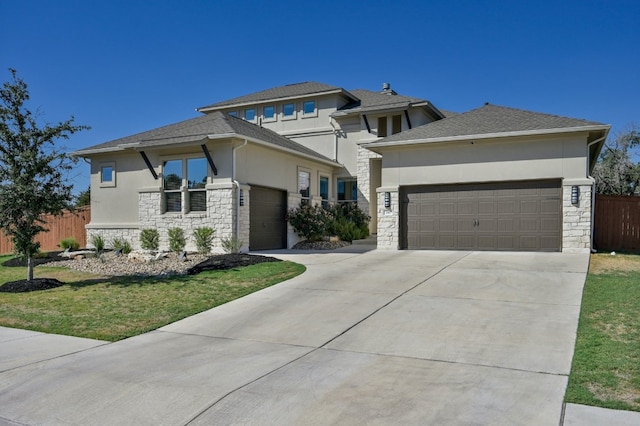 prairie-style house with stucco siding, stone siding, fence, concrete driveway, and a garage