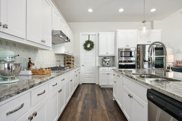 kitchen with tasteful backsplash, white cabinets, stainless steel appliances, wall chimney exhaust hood, and a sink