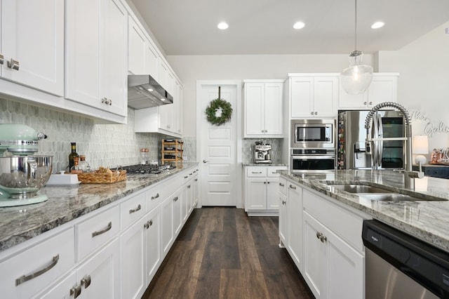 kitchen featuring wall chimney exhaust hood, a sink, dark wood-style flooring, white cabinetry, and appliances with stainless steel finishes