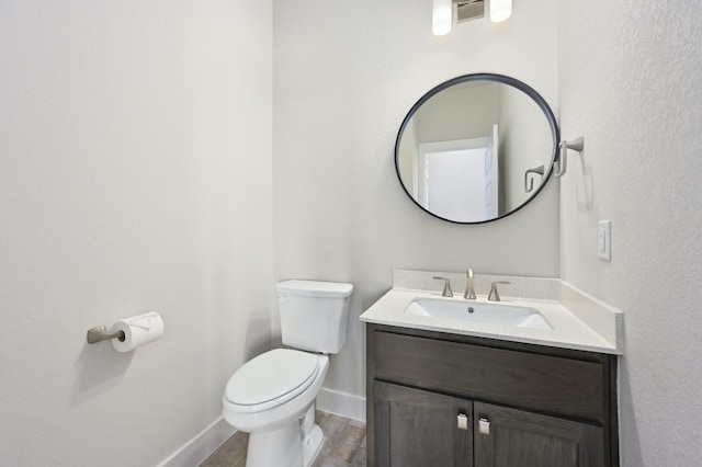 bathroom featuring baseboards, toilet, and vanity