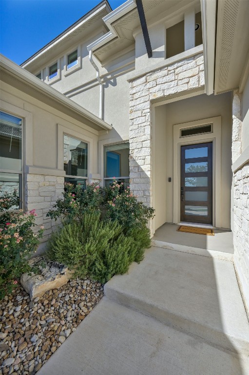 view of exterior entry with stone siding and stucco siding