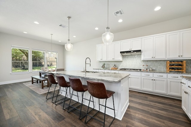 kitchen with under cabinet range hood, visible vents, backsplash, and stainless steel gas cooktop