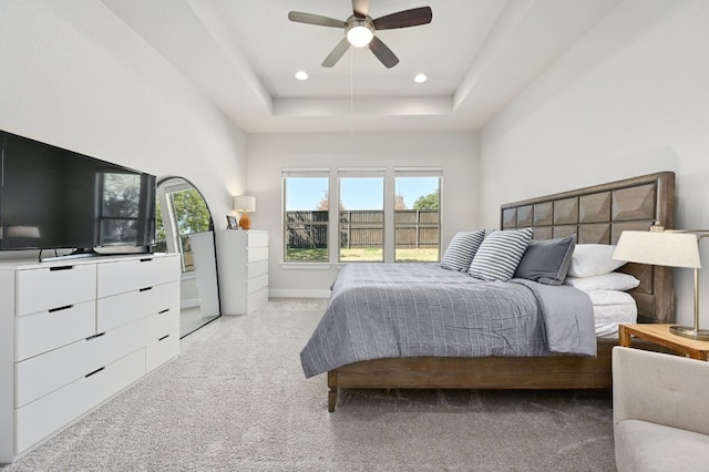 bedroom featuring baseboards, light colored carpet, a tray ceiling, recessed lighting, and a ceiling fan