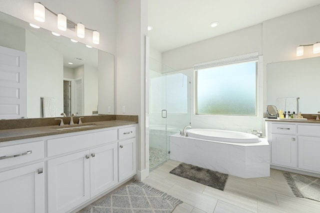 bathroom featuring visible vents, two vanities, a stall shower, a sink, and a bath