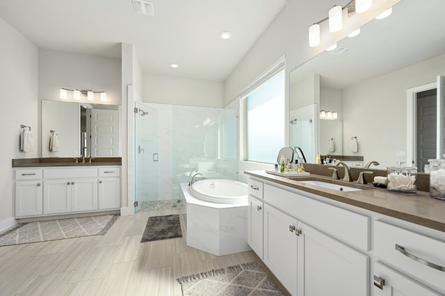 340 Axis Loop, Georgetown, TX 78628 - bathroom featuring a shower stall, a bath, two vanities, and recessed lighting