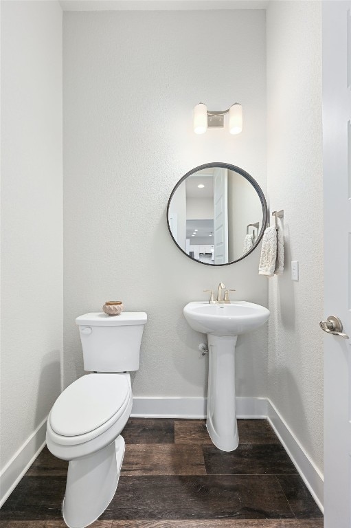 bathroom featuring toilet, wood finished floors, baseboards, and a sink