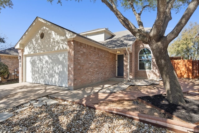 view of front of house featuring brick siding, concrete driveway, an attached garage, and fence